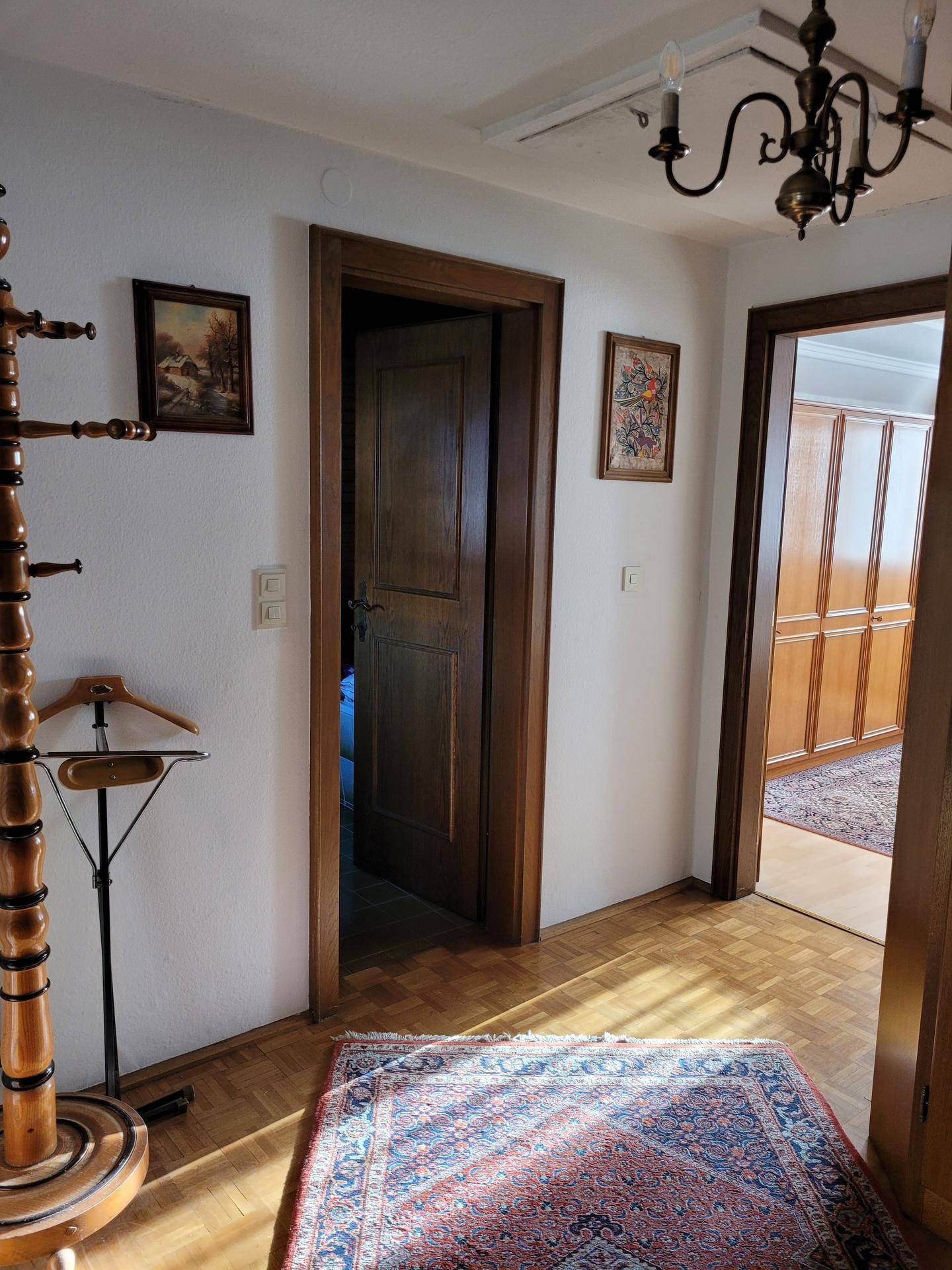 Heller Flur mit Parkettboden, Holztüren und traditioneller Garderobe.