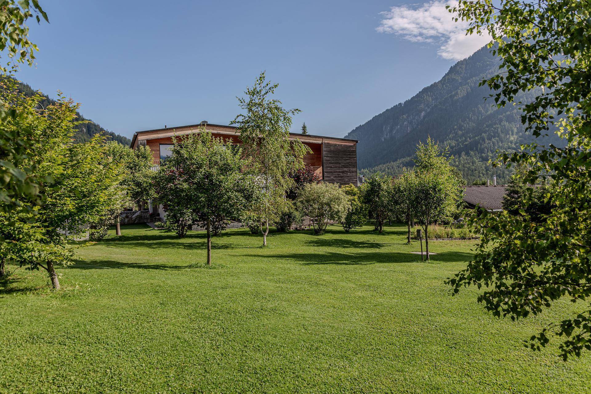 Die moderne Villa ist umgeben von einem weitläufigen, gepflegten Garten mit jungen Bäumen.
