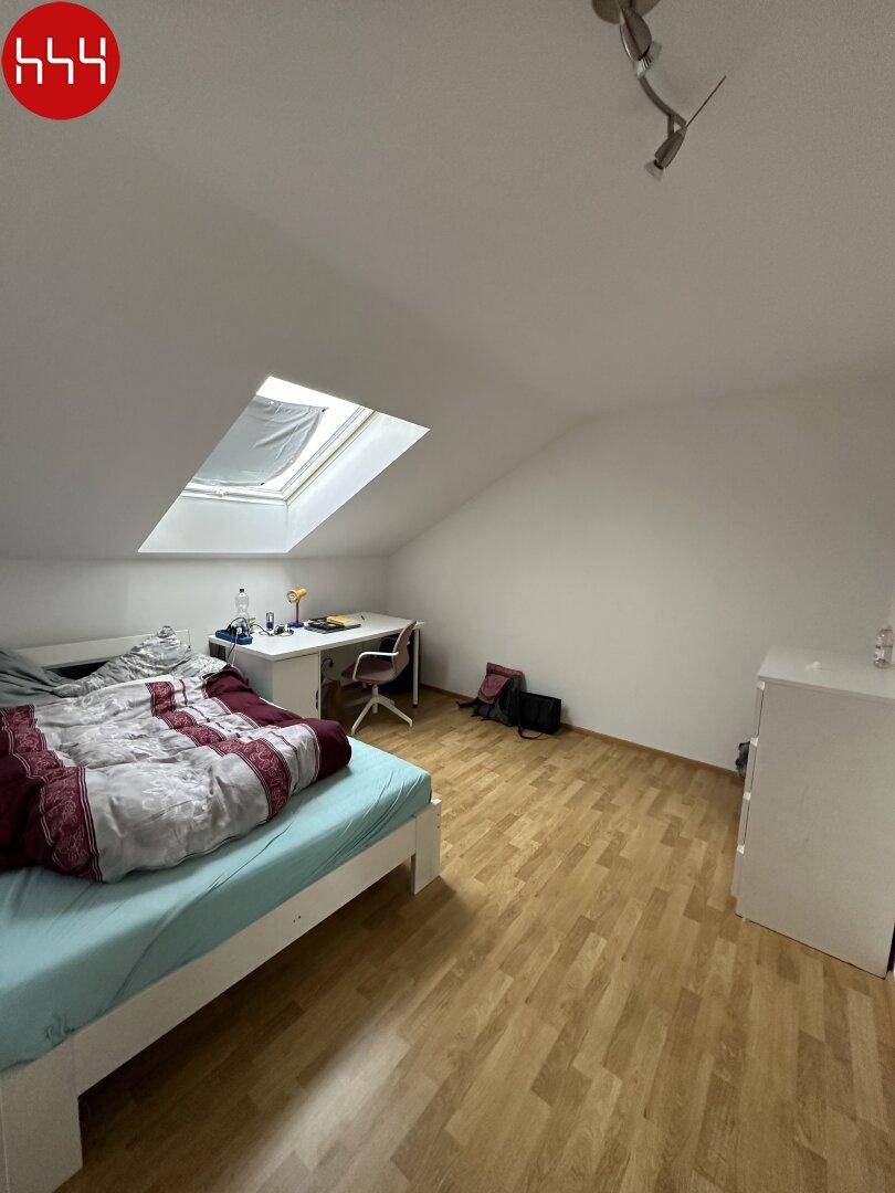 Schlafzimmer mit Holzboden, Dachschräge und großem Dachfenster für viel Licht.