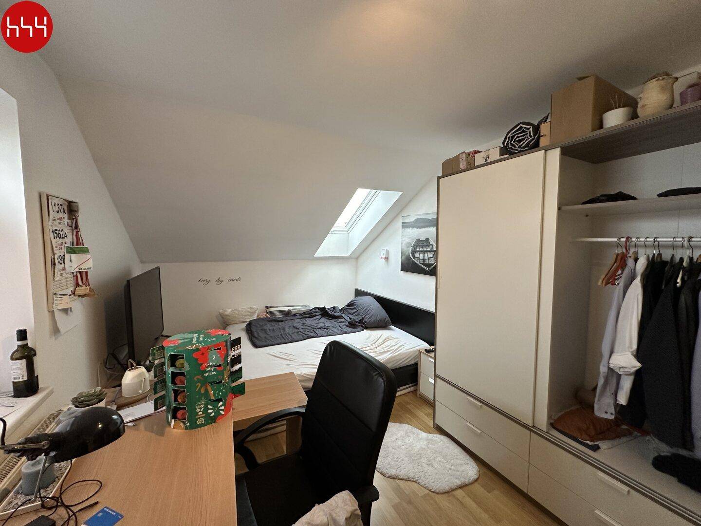 Gemütliches Schlafzimmer mit Kleiderschrank, Schreibtisch und Dachfenster.
