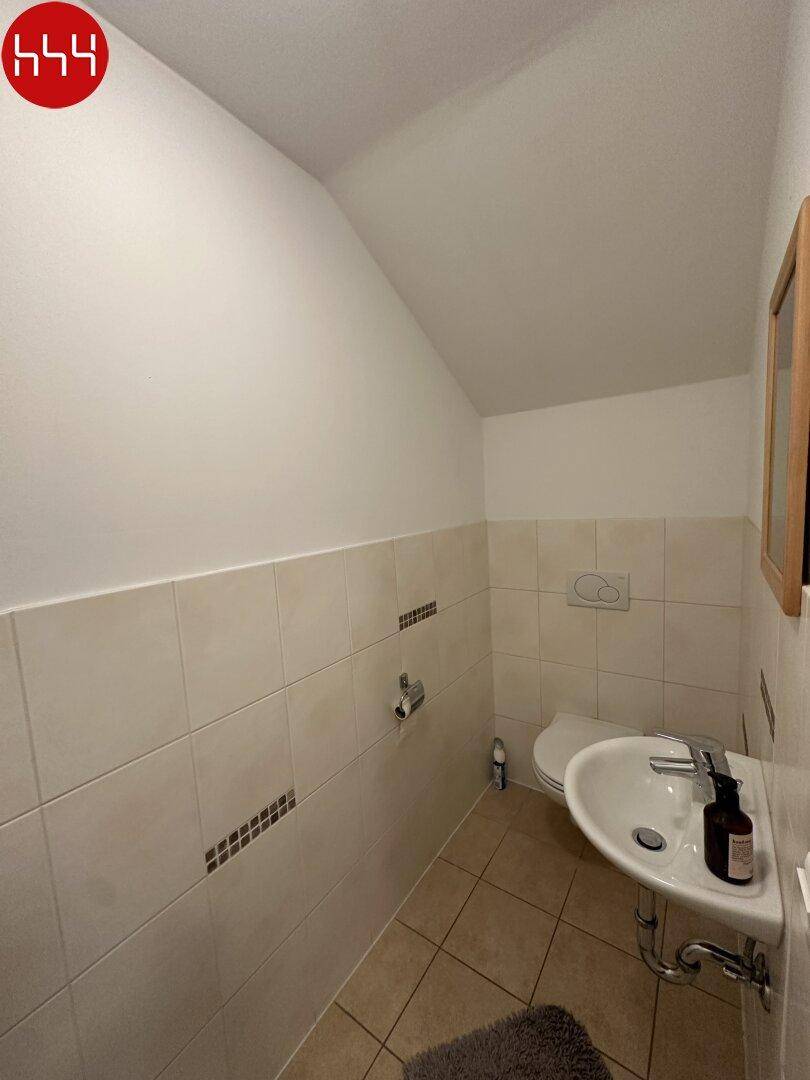 Kleines Gäste-WC mit Waschbecken, Toilette und hellen Fliesen.