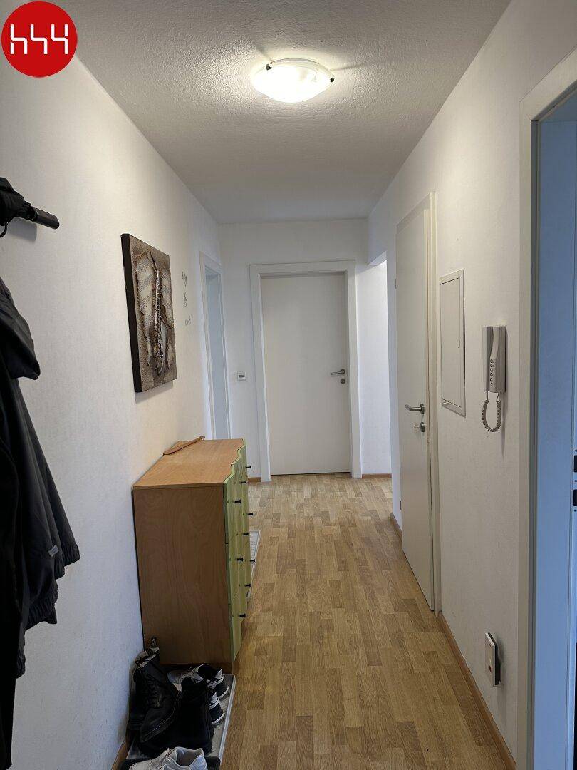 Langer Flur mit Parkettboden und Garderobe, der zu weiteren Räumen führt.
