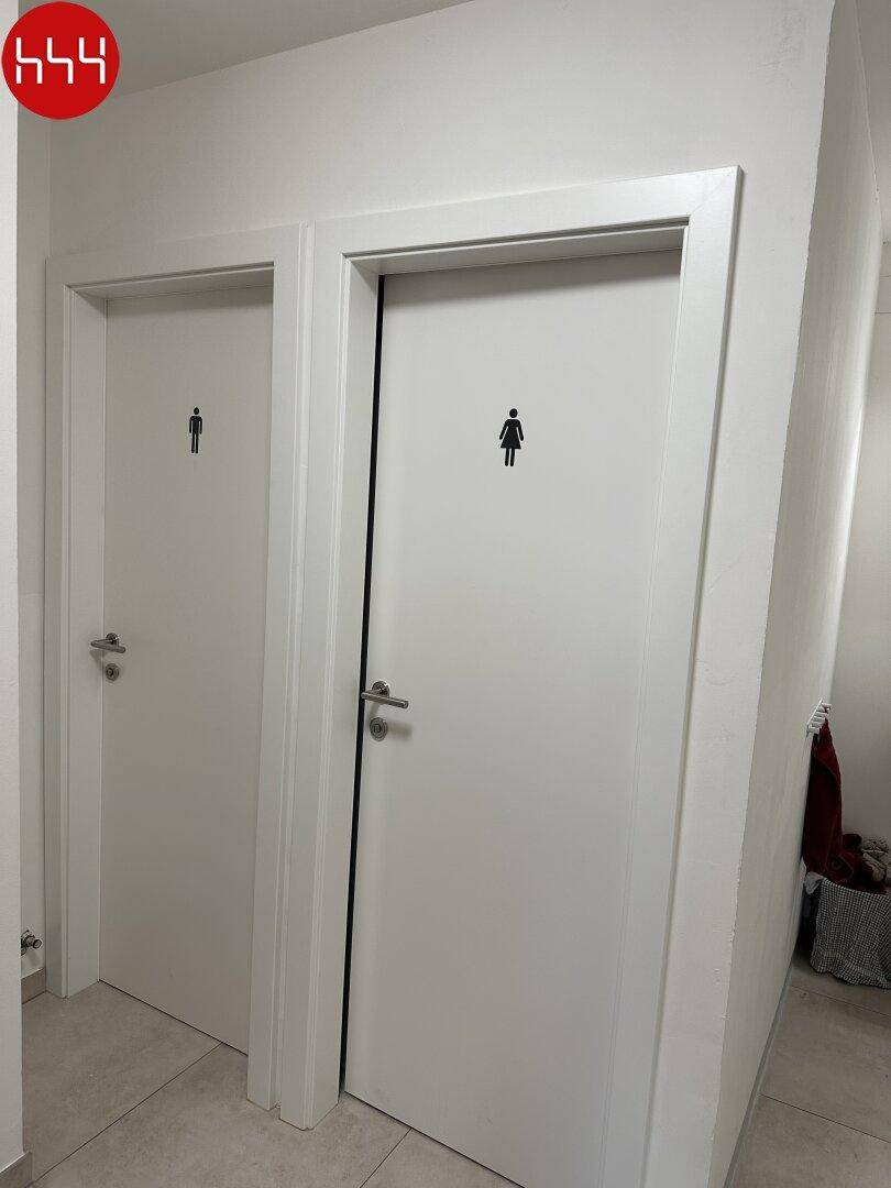 Zwei separate Toilettentüren mit Piktogrammen für Damen und Herren in einem hellen, gepflegten Flur.