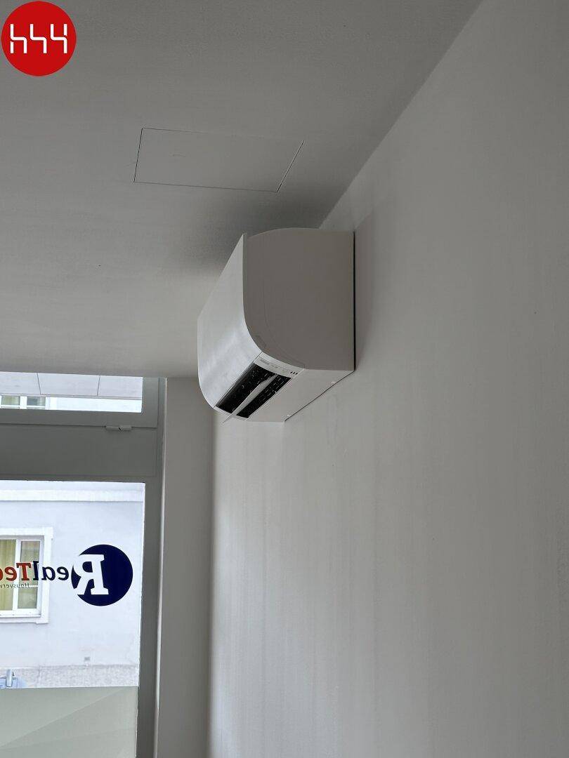 Eine moderne, weiße Klimaanlage ist unauffällig an der Wand montiert, um den Raum effizient zu kühlen.