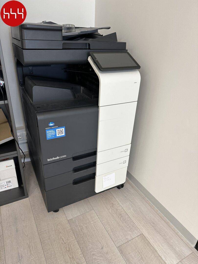Ein großer, moderner Multifunktionsdrucker steht in einer Ecke eines Büros auf einem hellen Laminatboden.