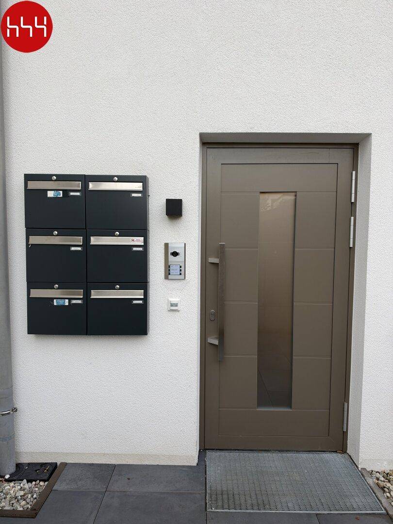 Haupteingang des Gebäudes mit moderner Tür, Briefkästen und Gegensprechanlage.