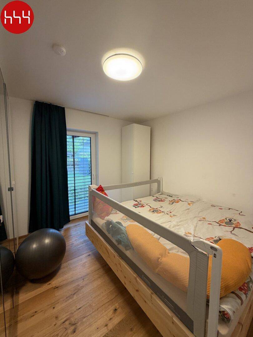 Gemütliches Schlafzimmer mit Holzboden, Fenster und einem Kleiderschrank.