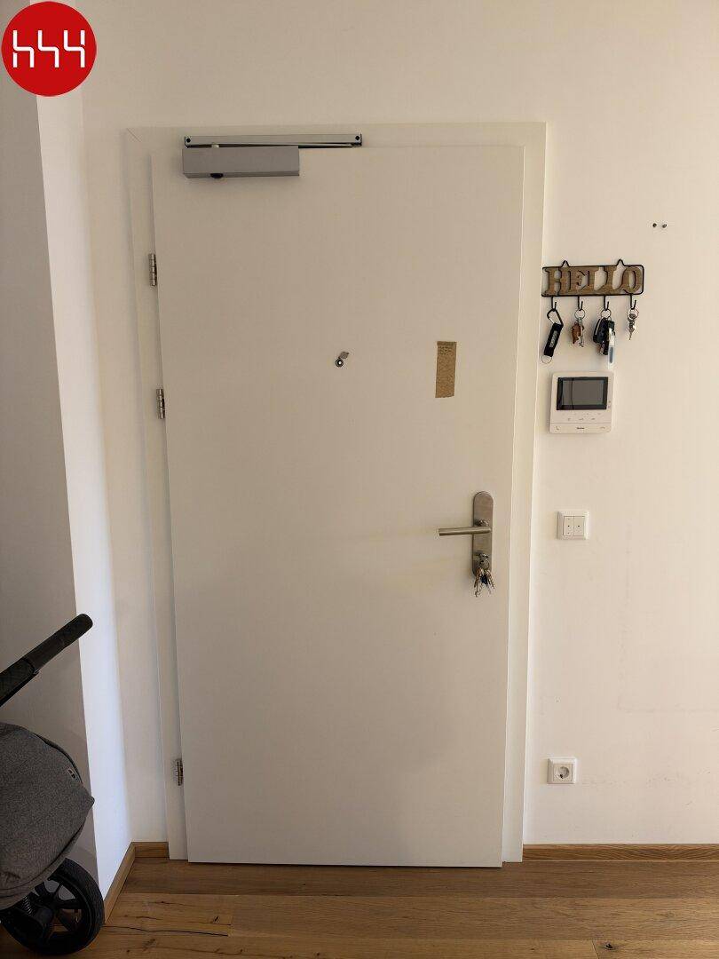 Eingangstür mit Sicherheitssystem und Schlüsselbrett in einem hellen Flur.