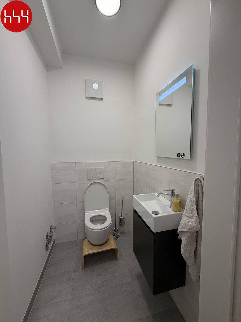 Modernes Gäste-WC mit wandhängender Toilette und kleinem Waschtisch.