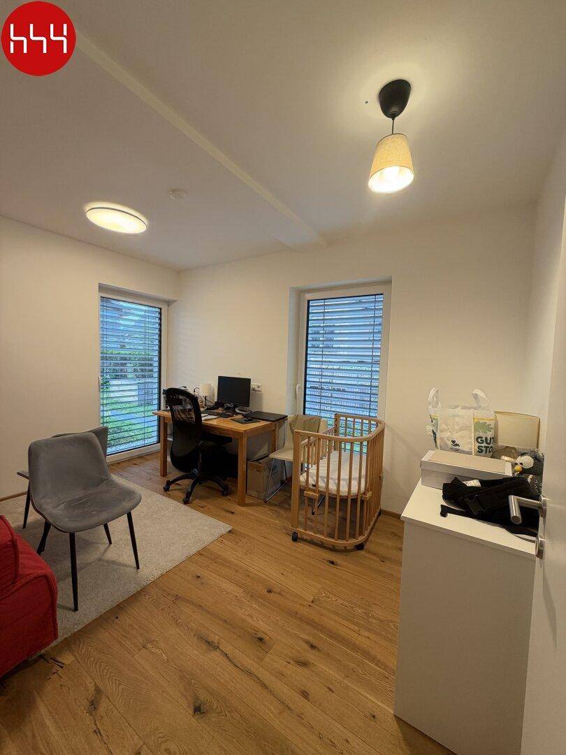 Vielseitig nutzbares Zimmer mit Schreibtisch, Kinderbett und Holzboden.