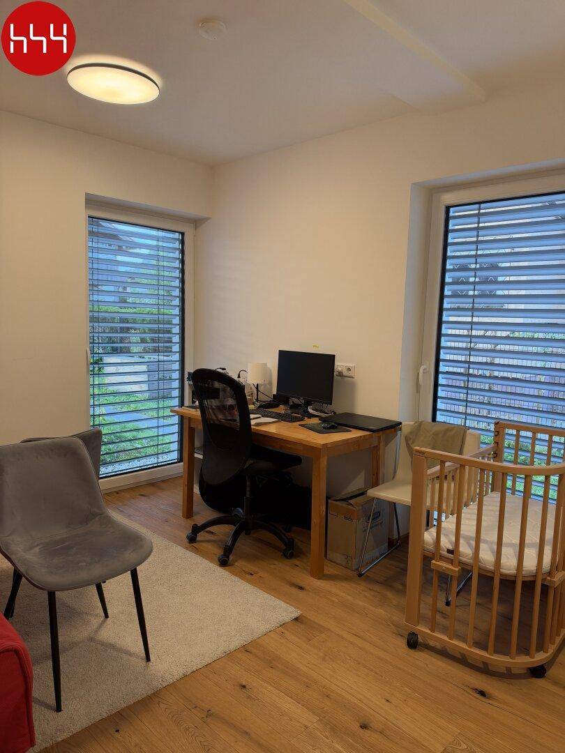 Arbeitsbereich mit Schreibtisch und Bürostuhl, umgeben von großen Fenstern.