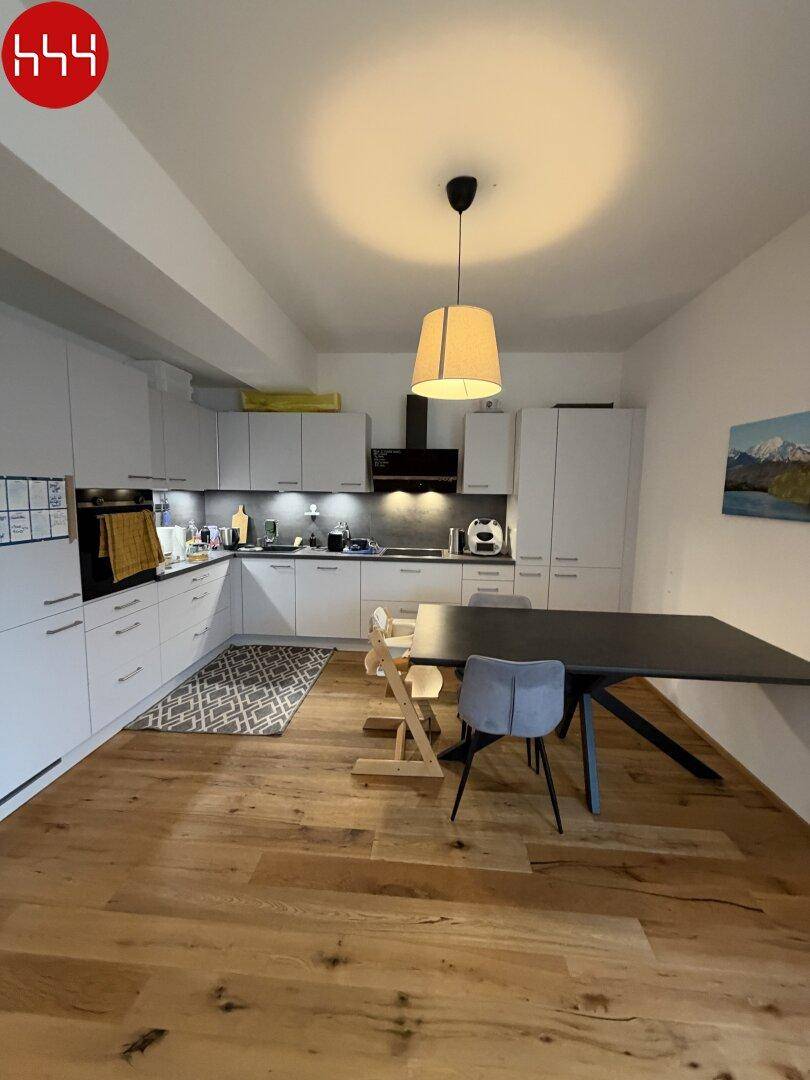 Helle, moderne Küche mit weißen Fronten, Holzboden und Essbereich für die Familie.