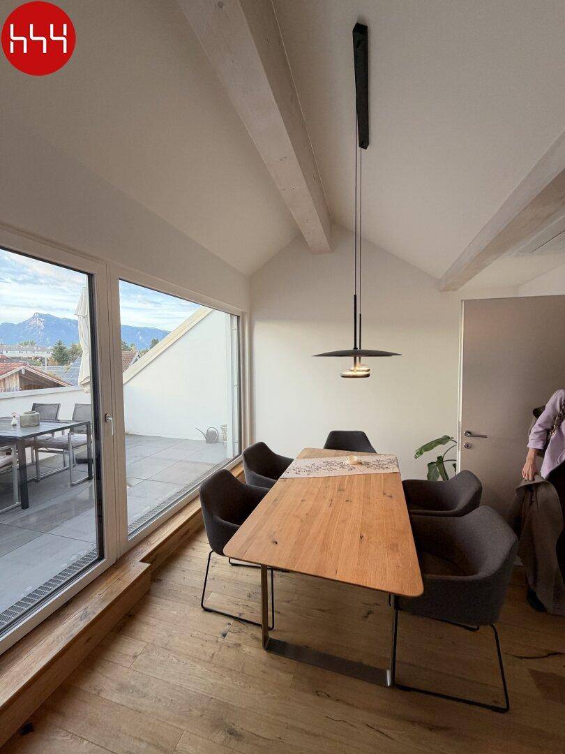 Essbereich mit Holztisch und Stühlen, direktem Zugang zur Terrasse und Panoramablick auf die Berge.