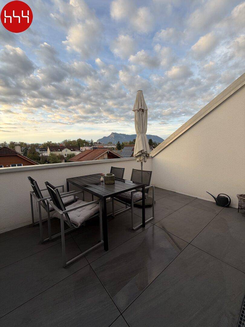 Geräumige Terrasse mit Esstisch, Sonnenschirm und weitem Blick auf die umliegende Berglandschaft.