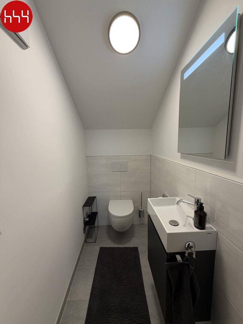 Modernes Gäste-WC mit Wand-WC, Waschbeckenunterschrank und Spiegel in minimalistischem Design.