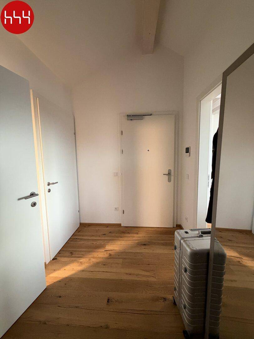 Heller Flur mit Holzboden und weiß gestrichenen Wänden, der zu den weiteren Räumen führt.