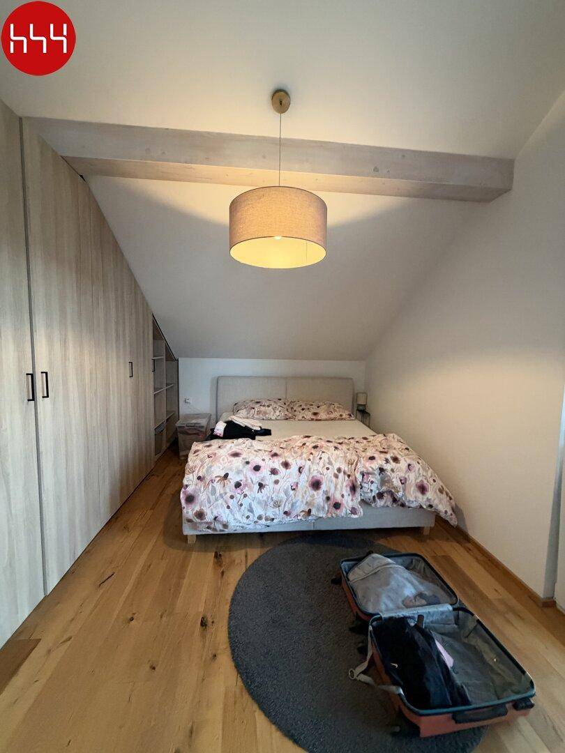 Gemütliches Schlafzimmer mit Holzboden, Einbauschränken und Dachschräge, die eine besondere Atmosphäre schafft.