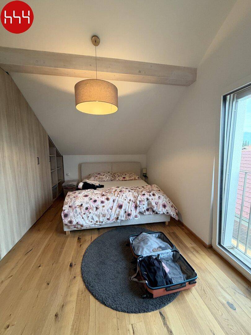 Gemütliches Schlafzimmer mit Holzboden, Einbauschränken und Dachschräge, die eine besondere Atmosphäre schafft.