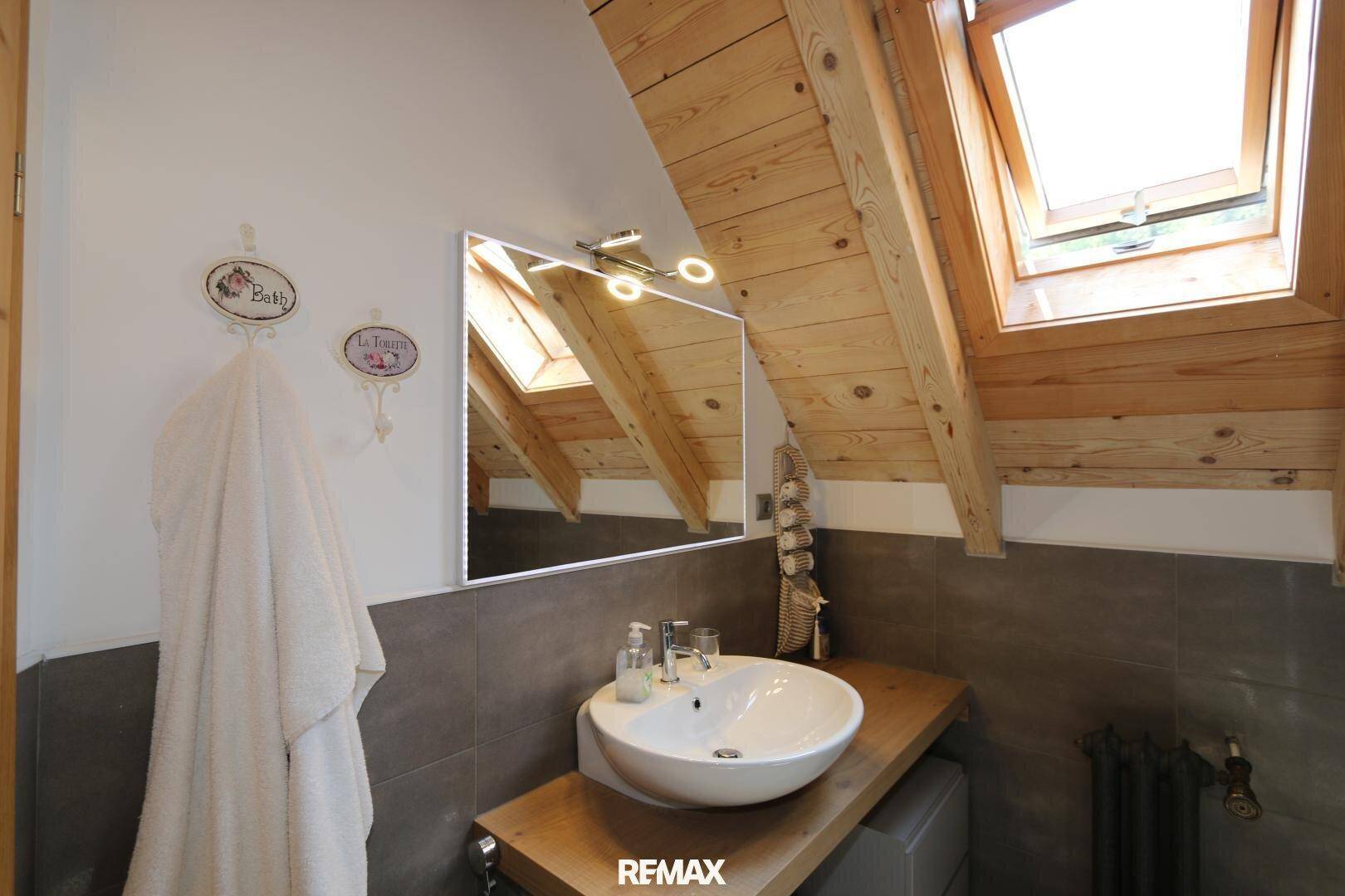 Modernes Badezimmer im Dachgeschoss mit Holzbalkendecke, Dachfenster und einem stilvollen Aufsatzwaschbecken.