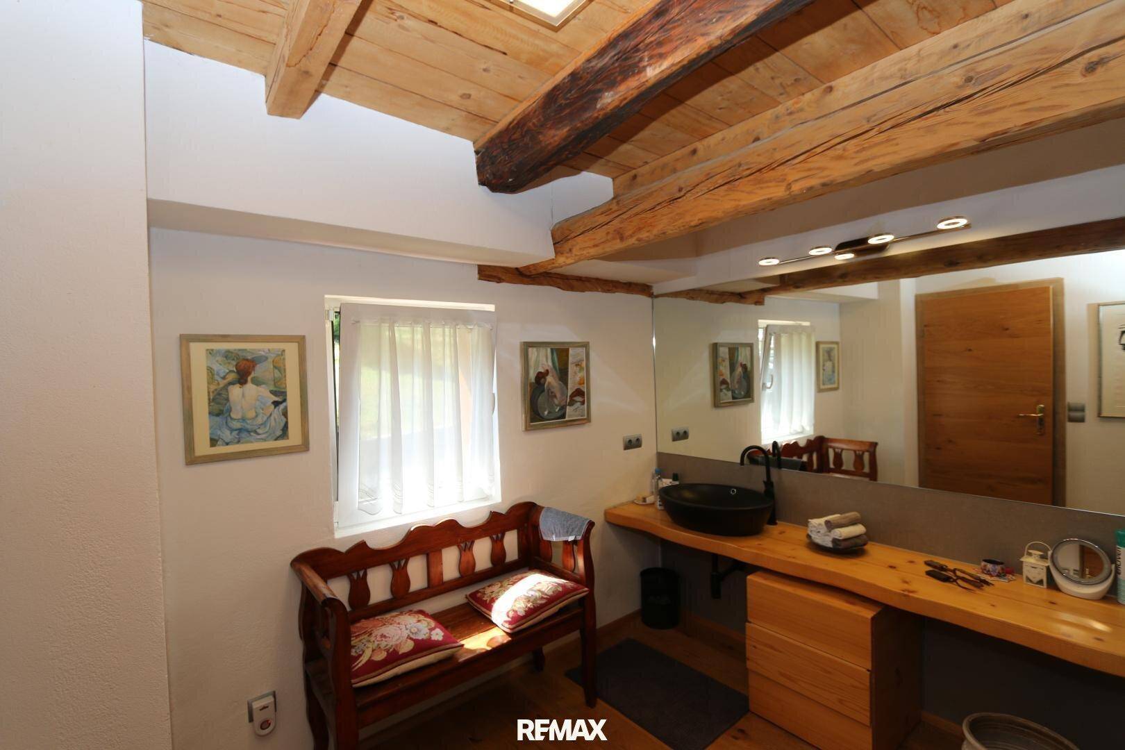 Badezimmer mit Holzwaschtisch, modernem Waschbecken und Holzbalkendecke.