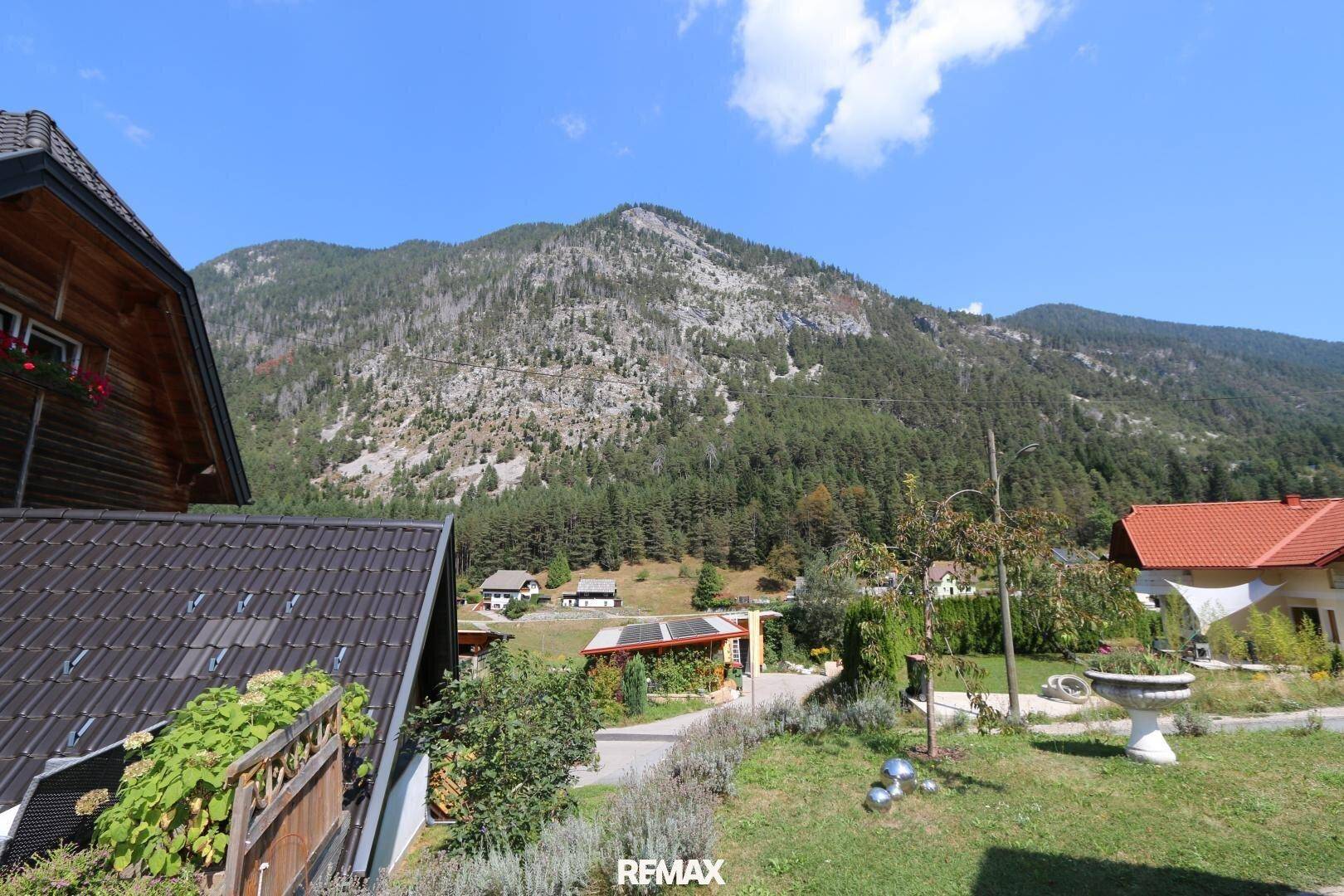 Weitläufiger Blick auf die umliegende Berglandschaft und die grüne Umgebung des Anwesens.