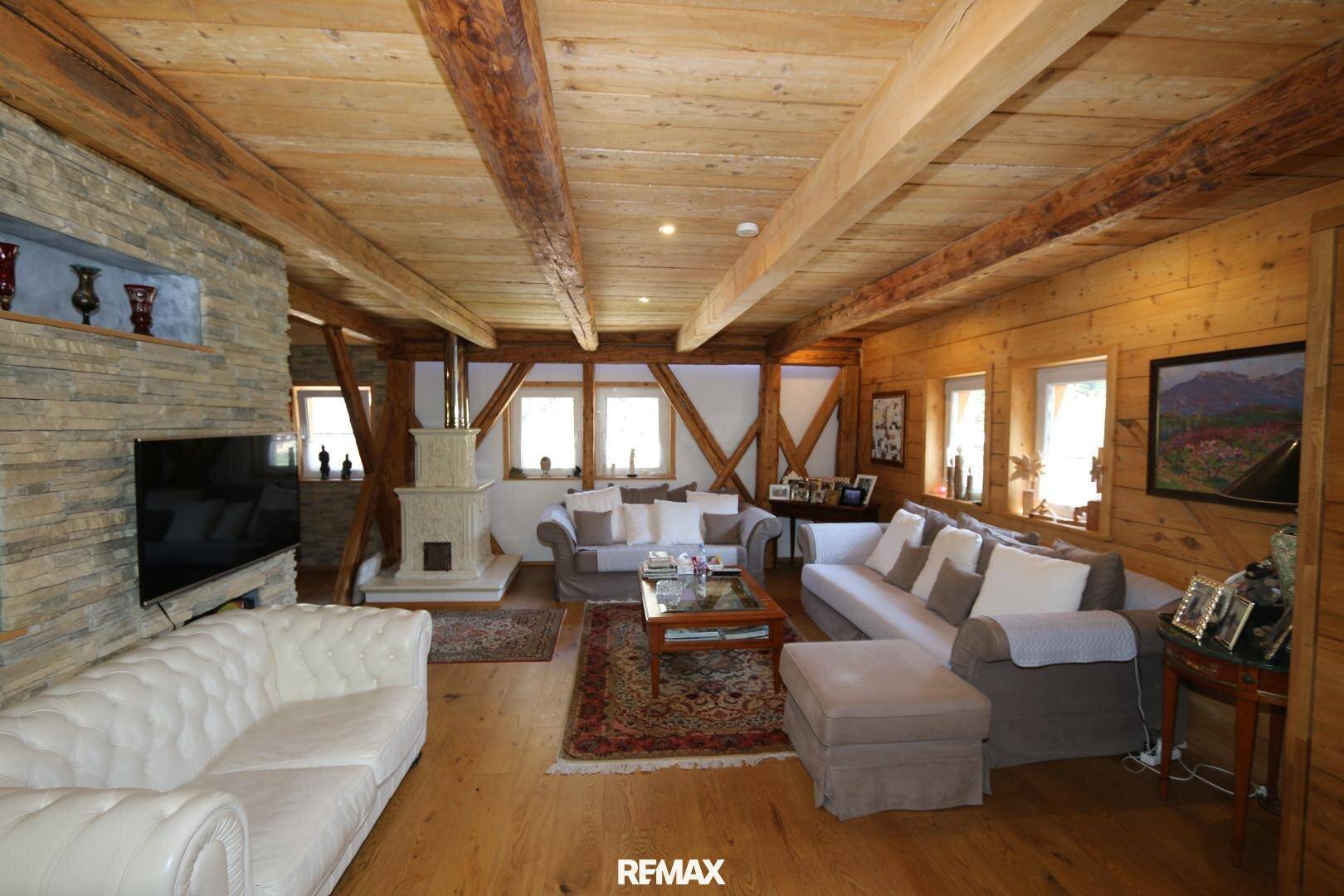 Rustikales Wohnzimmer mit Holzbalken, Kachelofen und Steinwandakzenten, sehr gemütlich.