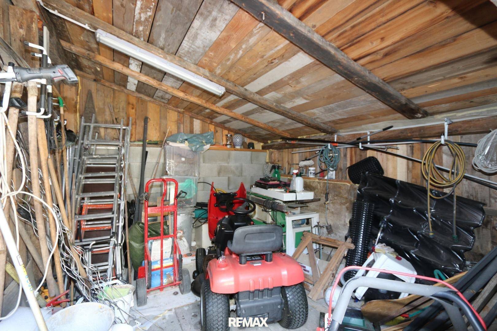 Rustikaler Werkstattraum mit Holzwänden, freiliegenden Balken und verschiedenen Werkzeugen sowie Geräten.
