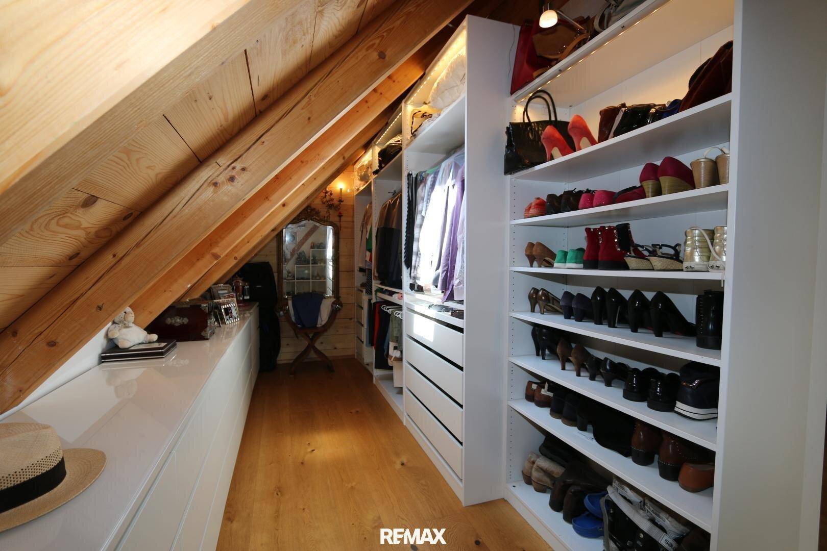 Geräumiger begehbarer Kleiderschrank mit Dachschräge und viel Stauraum für Kleidung.