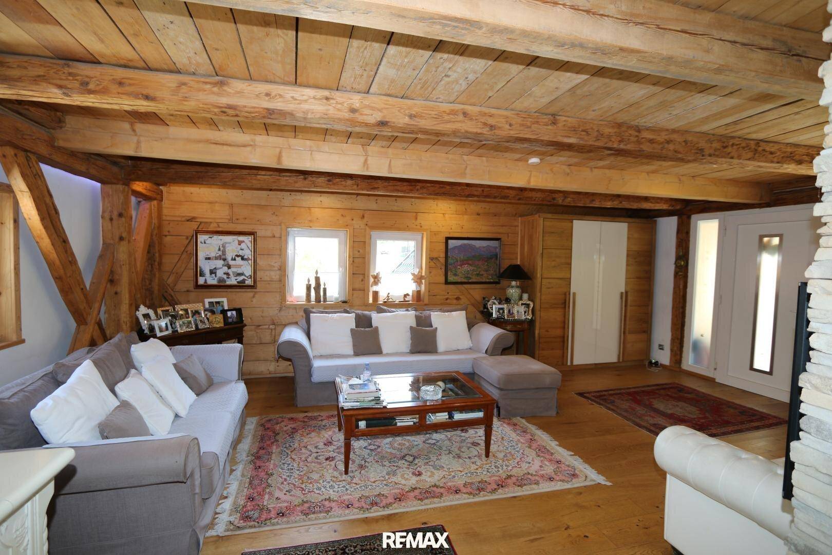 Gemütliches Wohnzimmer im alpinen Stil mit Holzbalkendecke und bequemen Sofas.