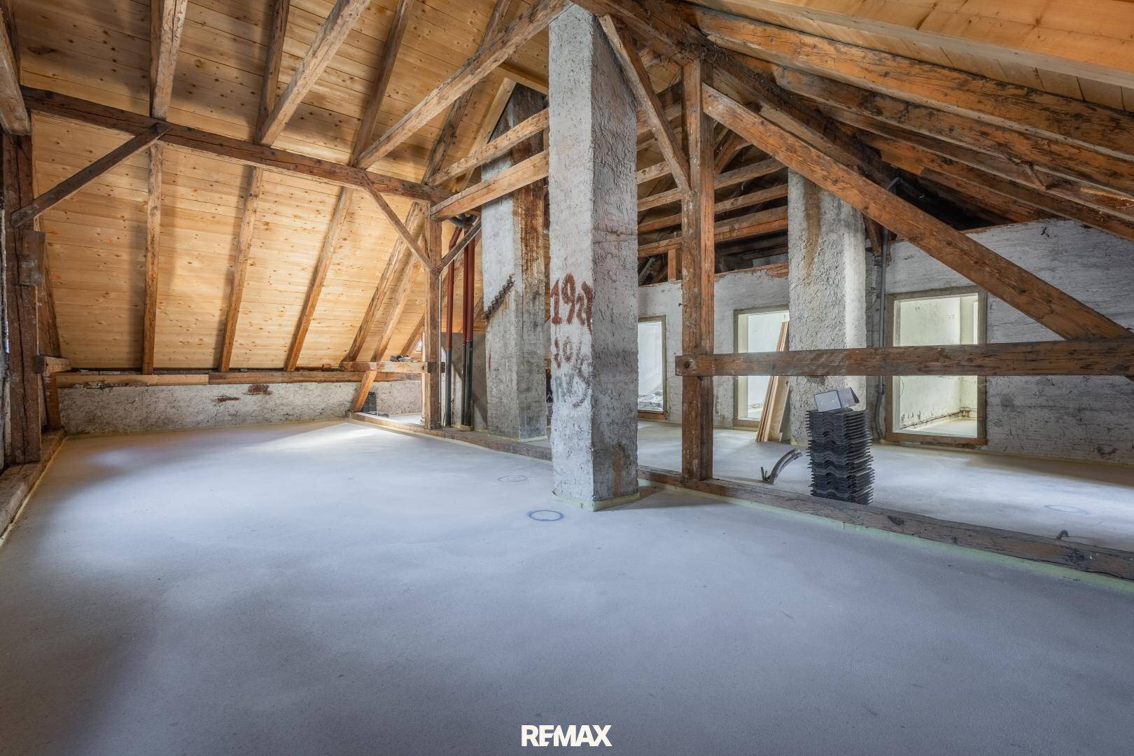 Geräumiger Dachboden mit freiliegenden Holzbalken und Betonboden, bietet viel Ausbaufläche.