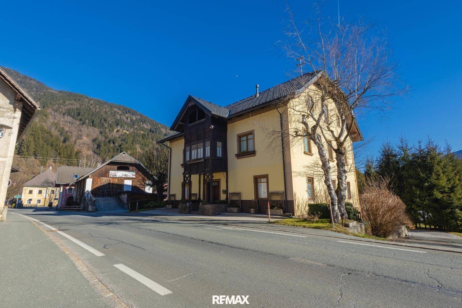 Vorderansicht des Hauses von der Straße aus, mit traditioneller Architektur und Bergblick im Hintergrund.