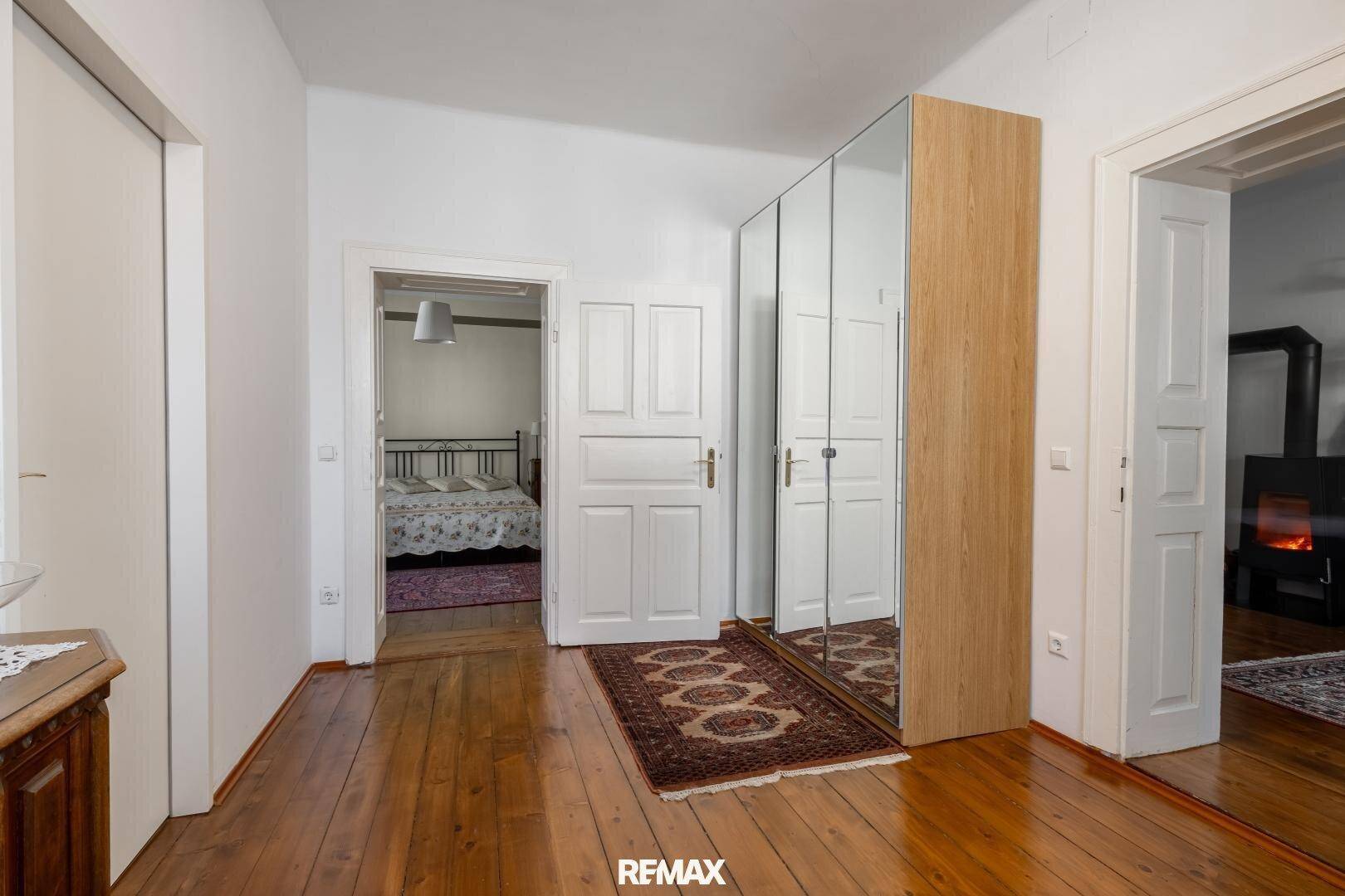 Geräumiger Flur mit Holzboden und Spiegelschrank, der zu einem Schlafzimmer führt.