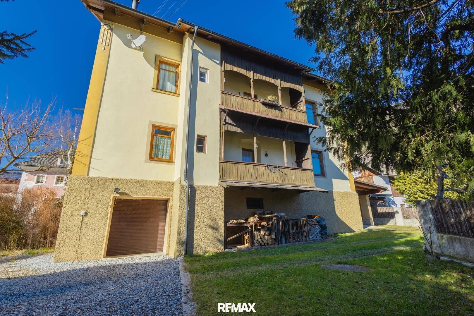 Seitenansicht des Hauses mit traditionellen Holzbalkonen und integrierter Garage im Erdgeschoss.