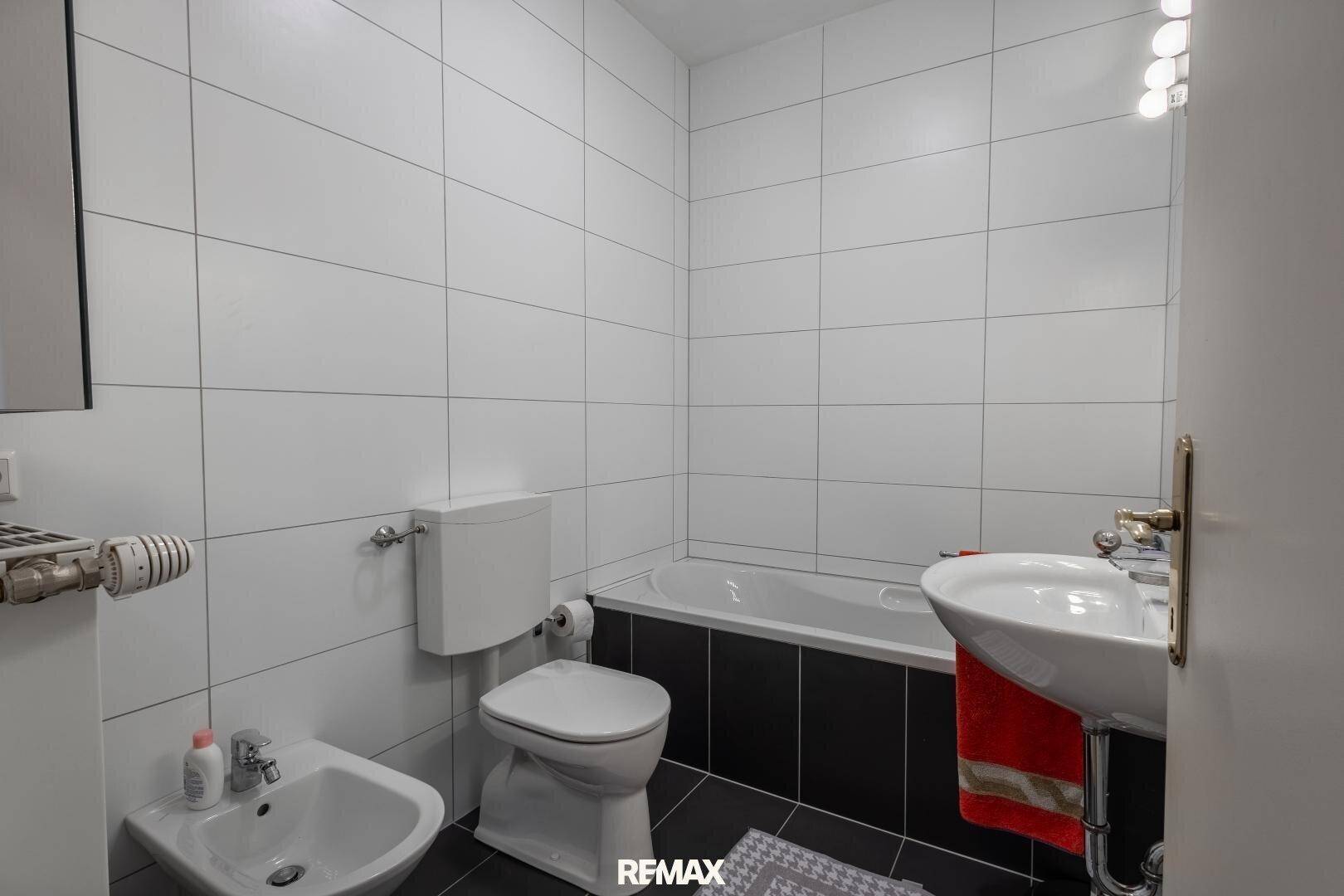 Funktionales Badezimmer mit Badewanne, Bidet und WC, ausgestattet mit weißen Wandfliesen.