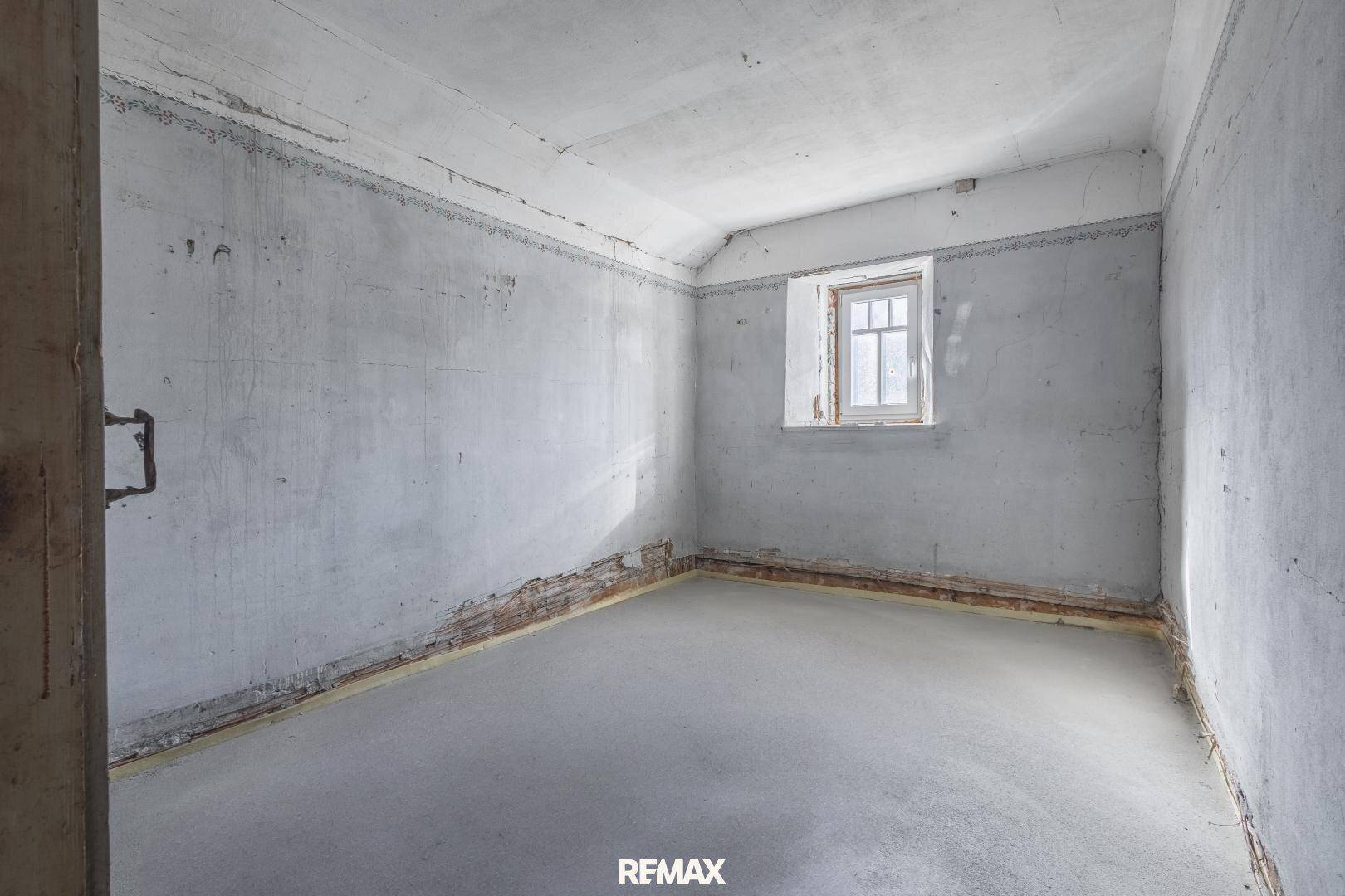 Leerer Raum mit Betonboden und rohen Wänden, bereit für den Ausbau.