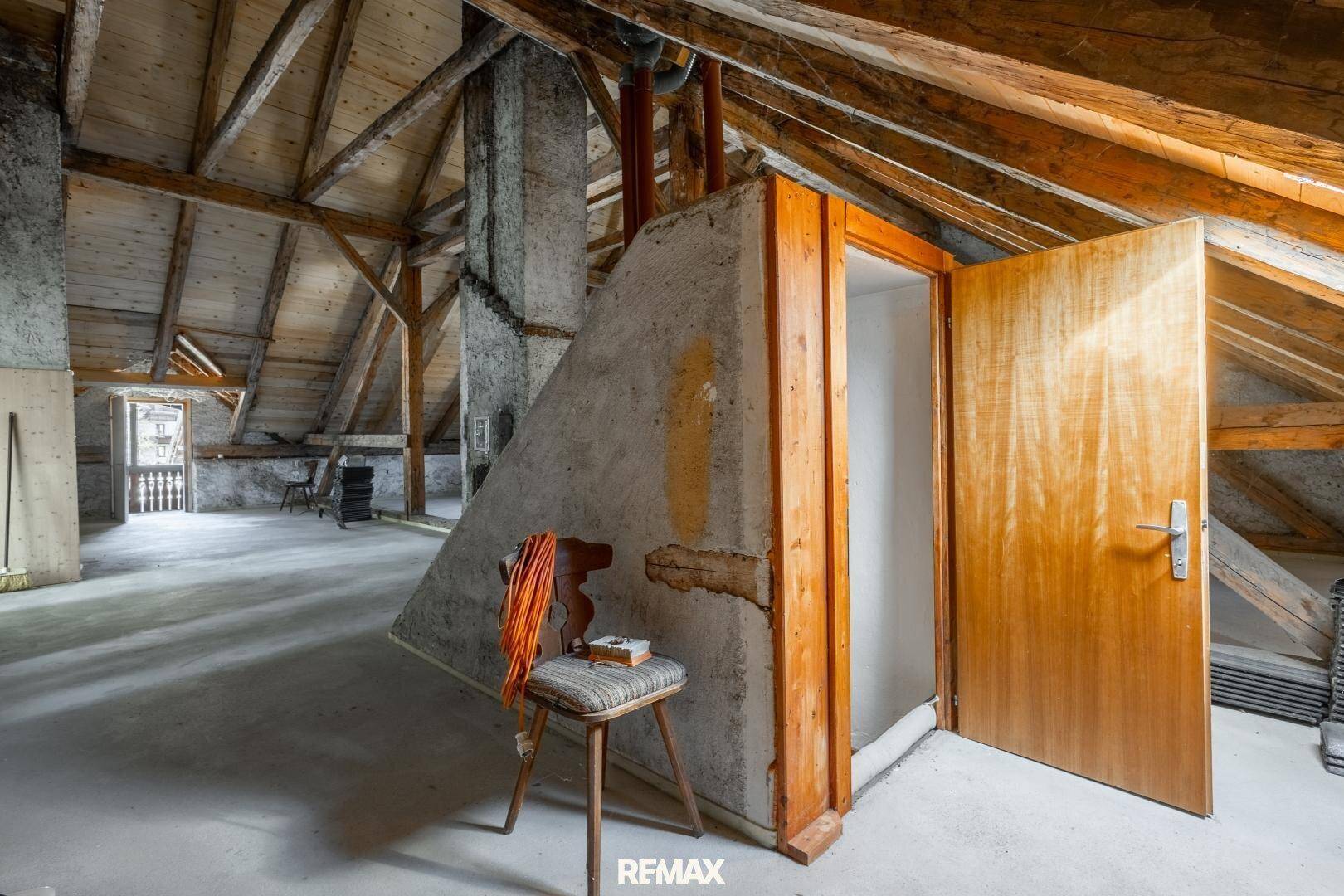 Unausgebauter Dachboden mit sichtbaren Holzbalken und rohen Wänden, bietet Ausbaupotenzial.