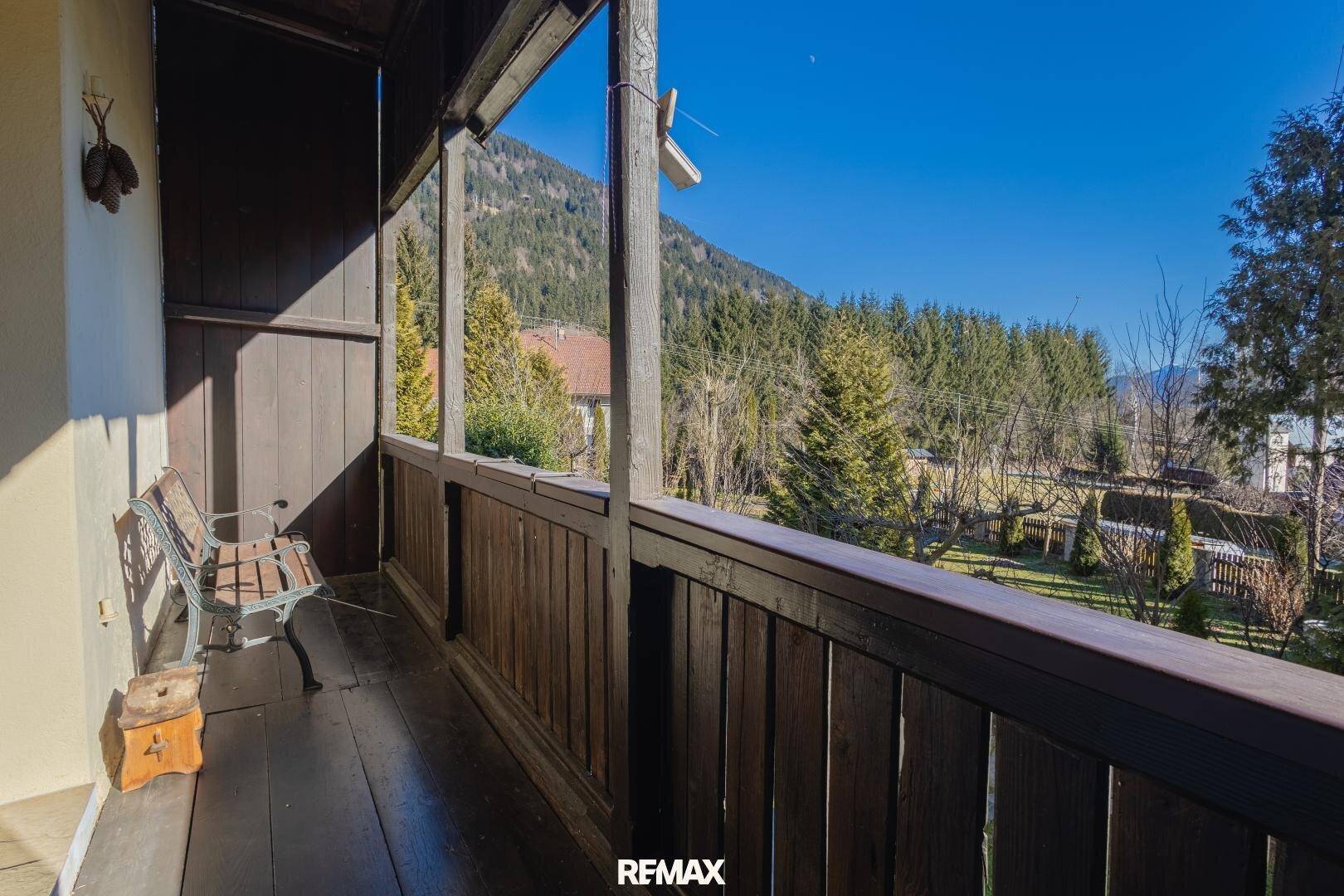 Rustikaler Holzbalkon mit Bergblick und Sitzbank, ideal für ruhige Momente im Freien.