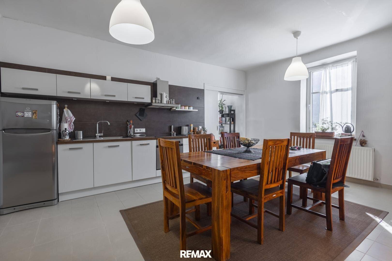 Moderne Wohnküche mit Essbereich, weißen Schränken und dunkler Arbeitsplatte, ideal für Familienmahlzeiten.