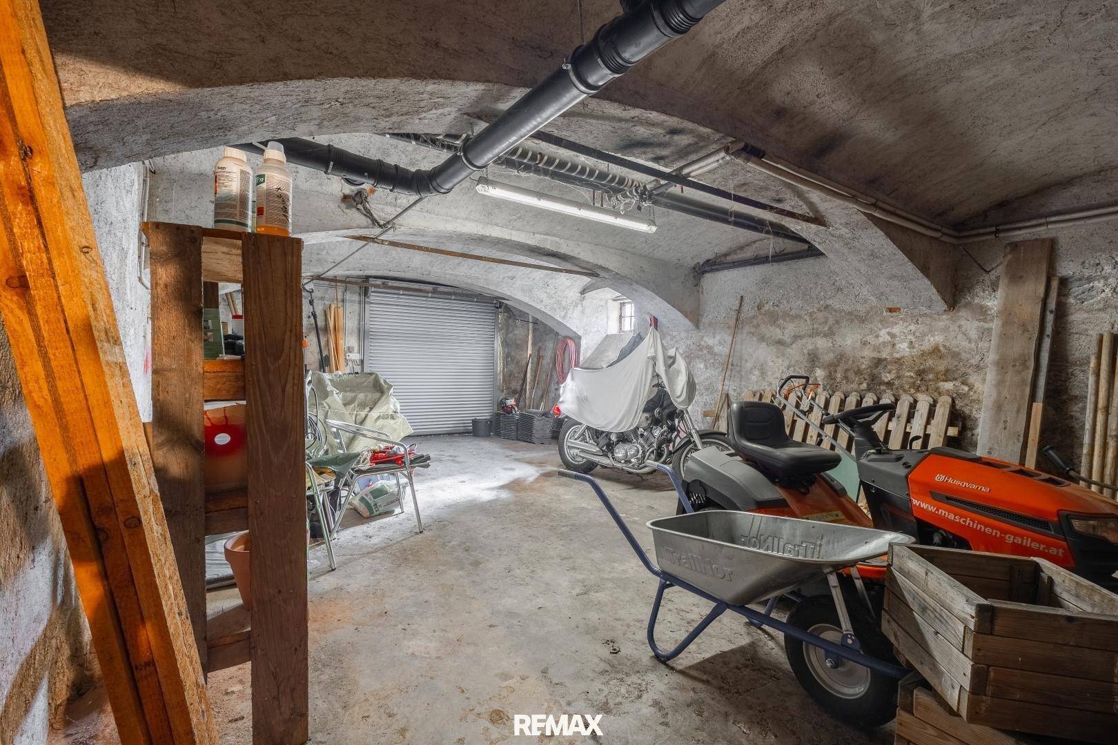 Großer Kellerraum mit Garagentor und gewölbter Decke, bietet viel Platz für Fahrzeuge und Lagerung.