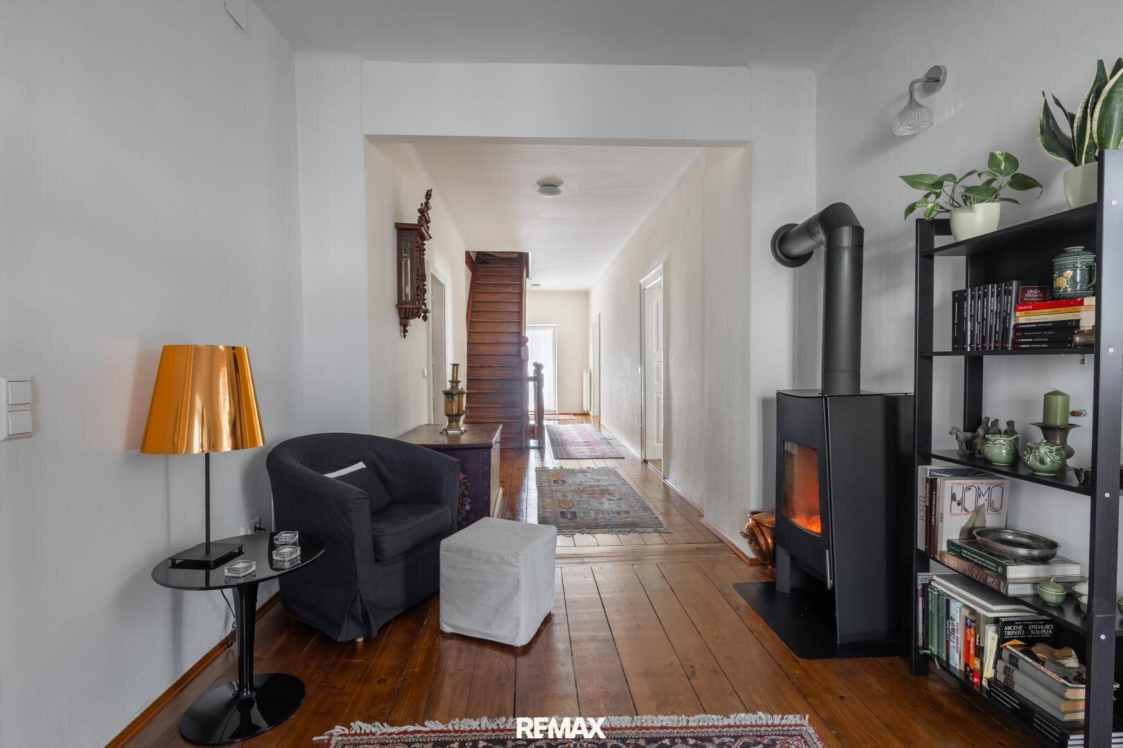 Heller Flur mit Holzboden, Kaminofen und Zugang zu weiteren Räumen sowie einer Treppe.