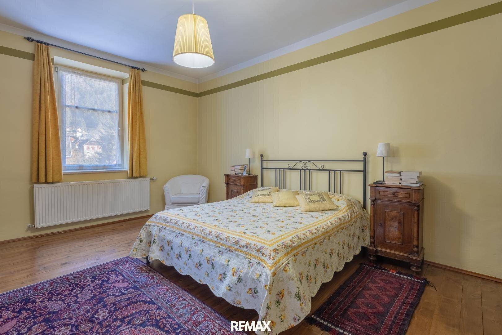 Gemütliches Schlafzimmer mit gelben Wänden, Holzboden und traditionellem Doppelbett, hell und einladend.