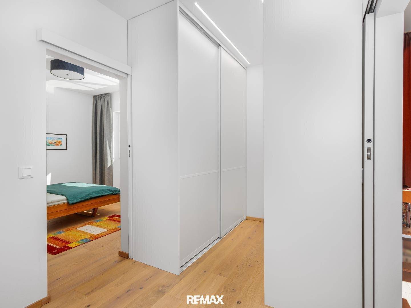 Heller Flur mit integriertem Schiebeschrank und Blick in ein gemütliches Schlafzimmer.