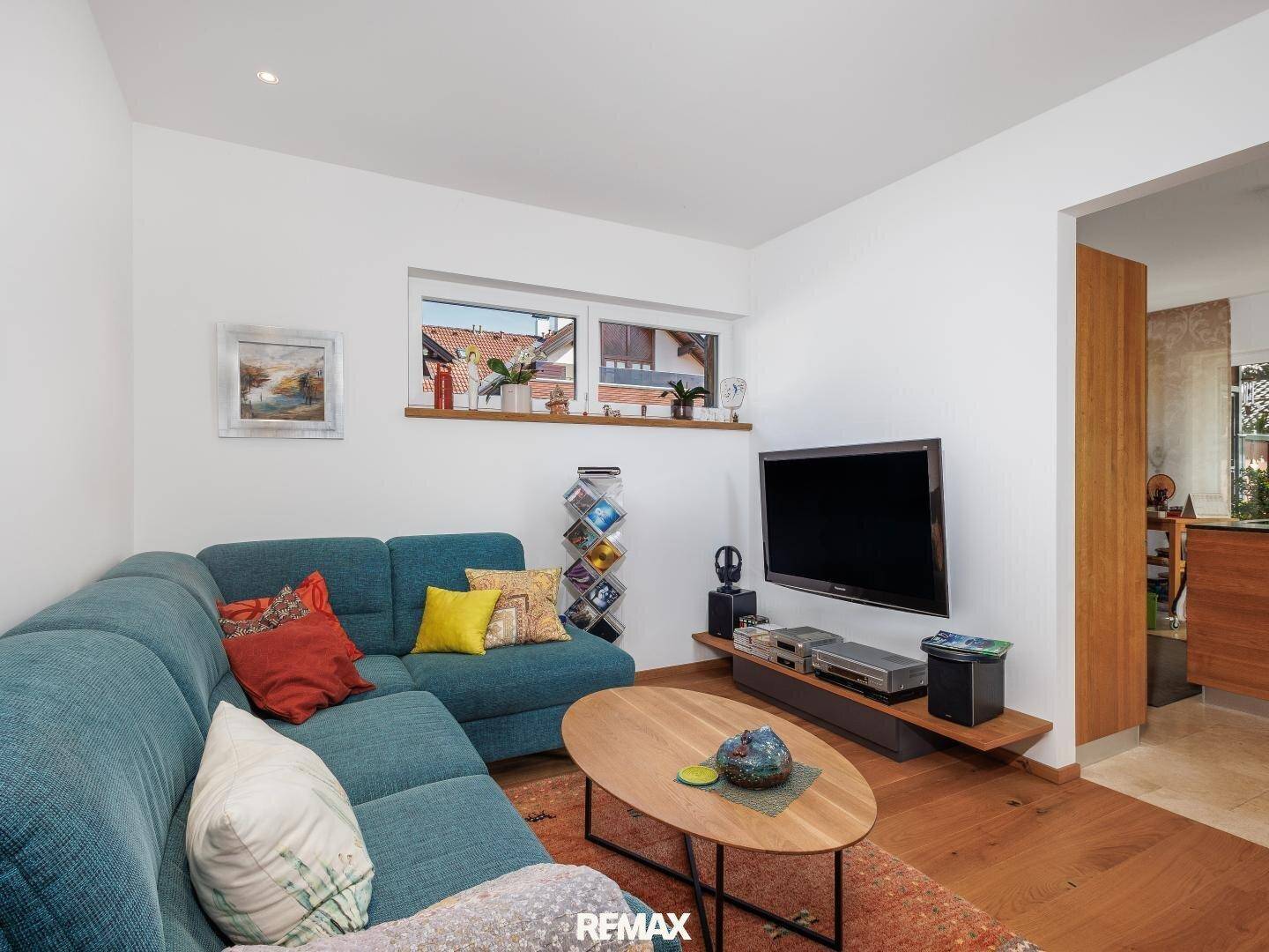 Gemütliches Wohnzimmer mit Ecksofa, Holzboden und Fernseher, ideal zum Entspannen.