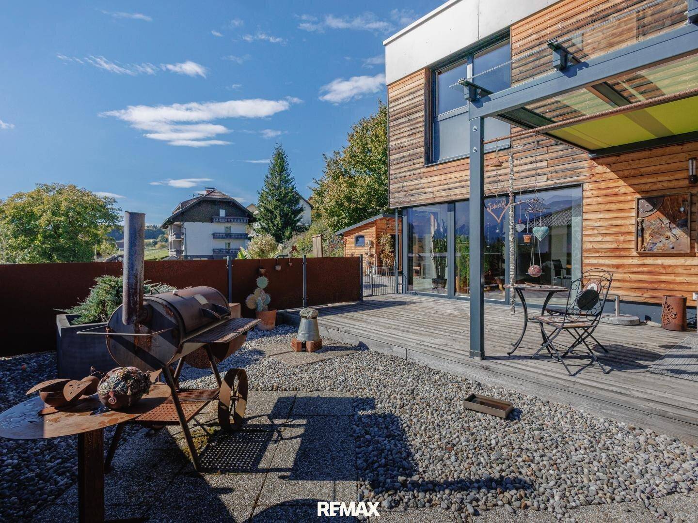 Geräumige Holzterrasse mit Grillbereich und Sitzgelegenheiten, ideal für entspannte Stunden im Freien.