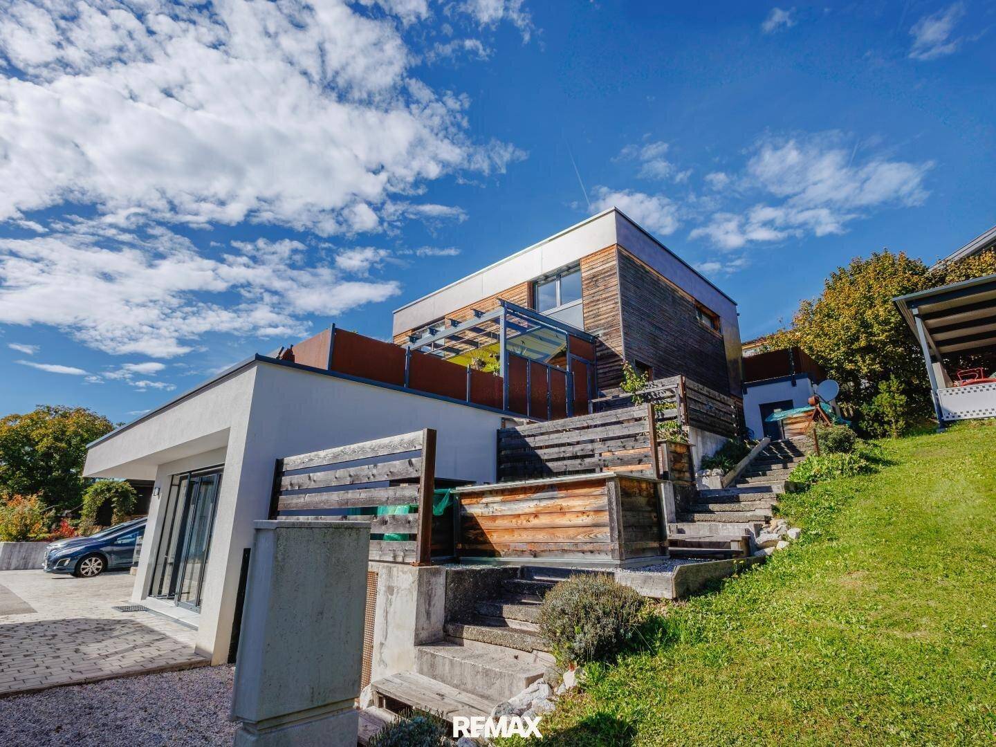 Moderne Architektur mit gestuften Gartenbereichen und Außentreppe, umgeben von viel Grün.