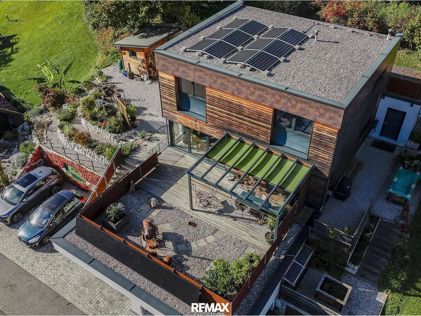 Zeitgenössisches Haus mit Photovoltaik auf dem Flachdach und einer großzügigen Terrasse mit Sitzbereich.