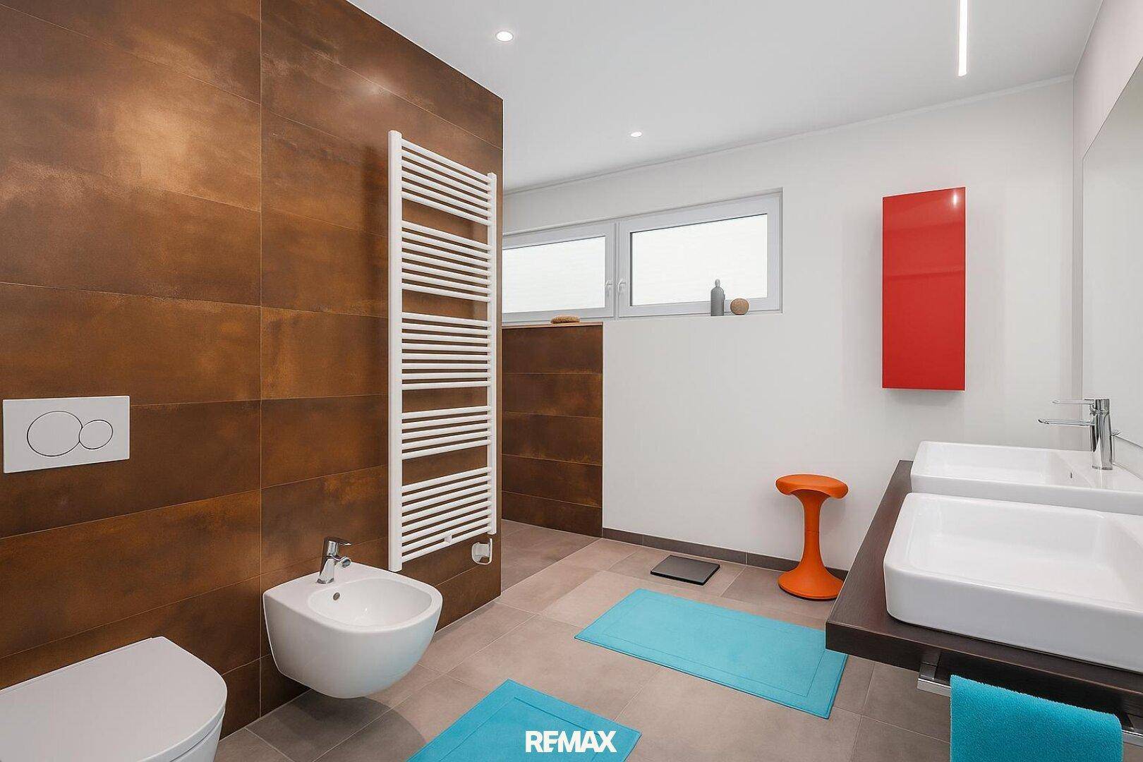 Modernes Badezimmer mit braunen Fliesen, Doppelwaschbecken, Bidet und beheiztem Handtuchhalter.