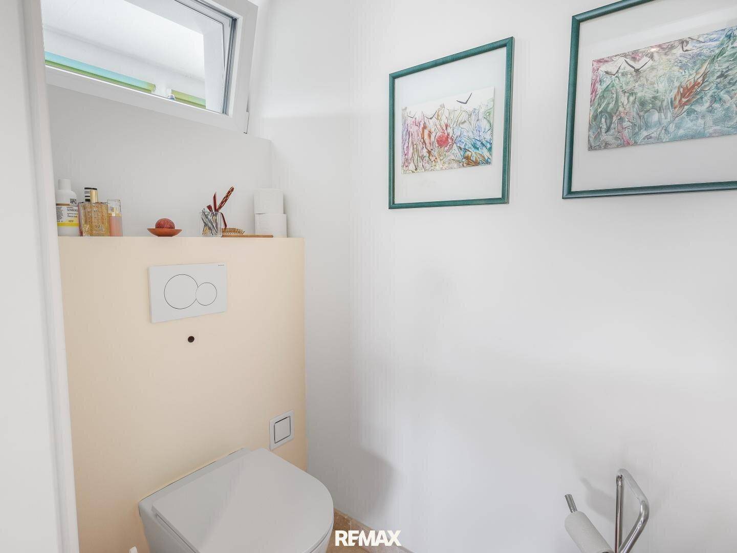 Helles Gäste-WC mit wandhängender Toilette und kleinem Fenster für natürliche Belüftung.