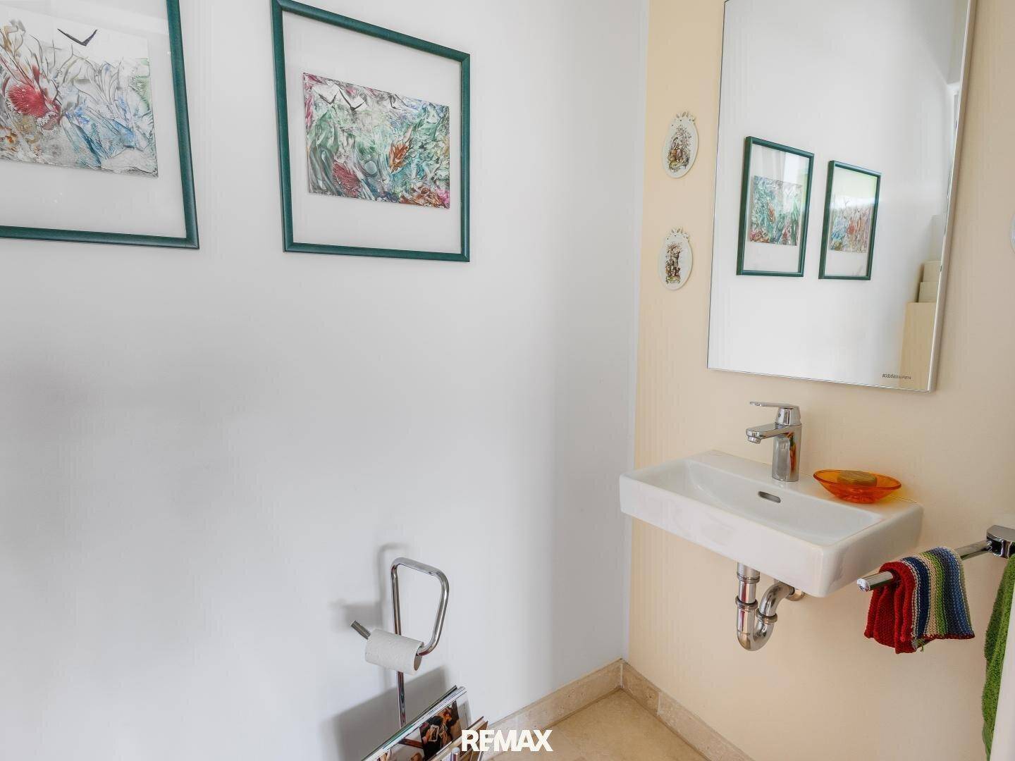Kleines Gäste-WC mit Waschbecken, Spiegel und heller Wandgestaltung.