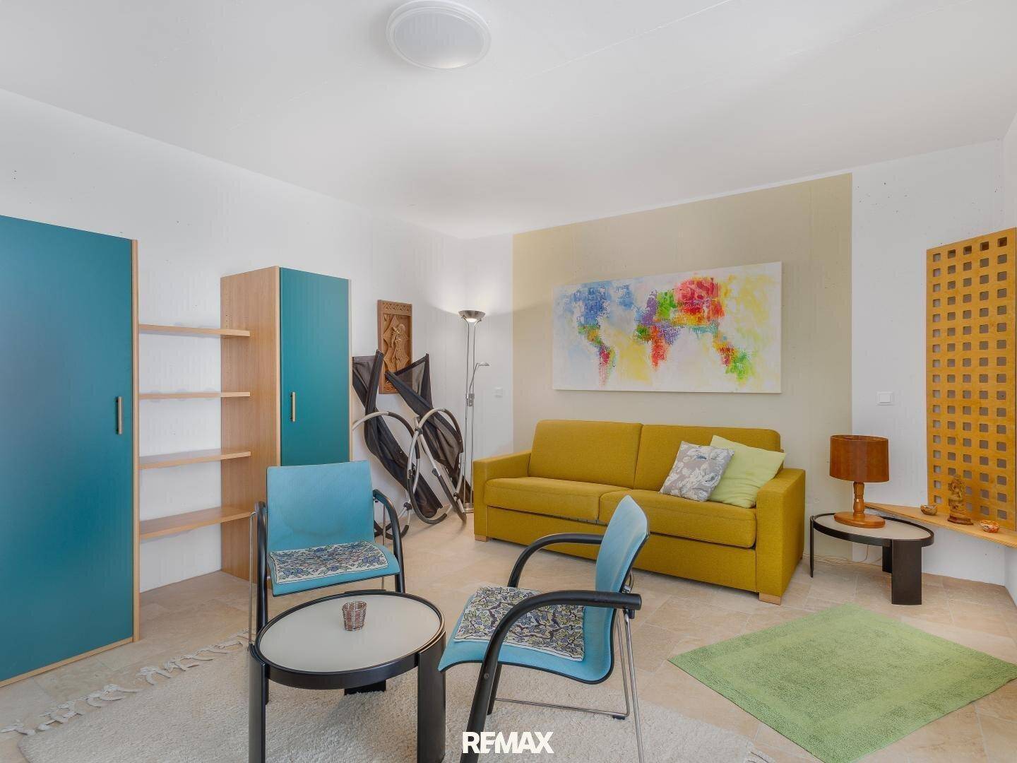 Freundliches Wohnzimmer mit gelbem Sofa, farbenfrohem Kunstwerk und modernen Möbeln.